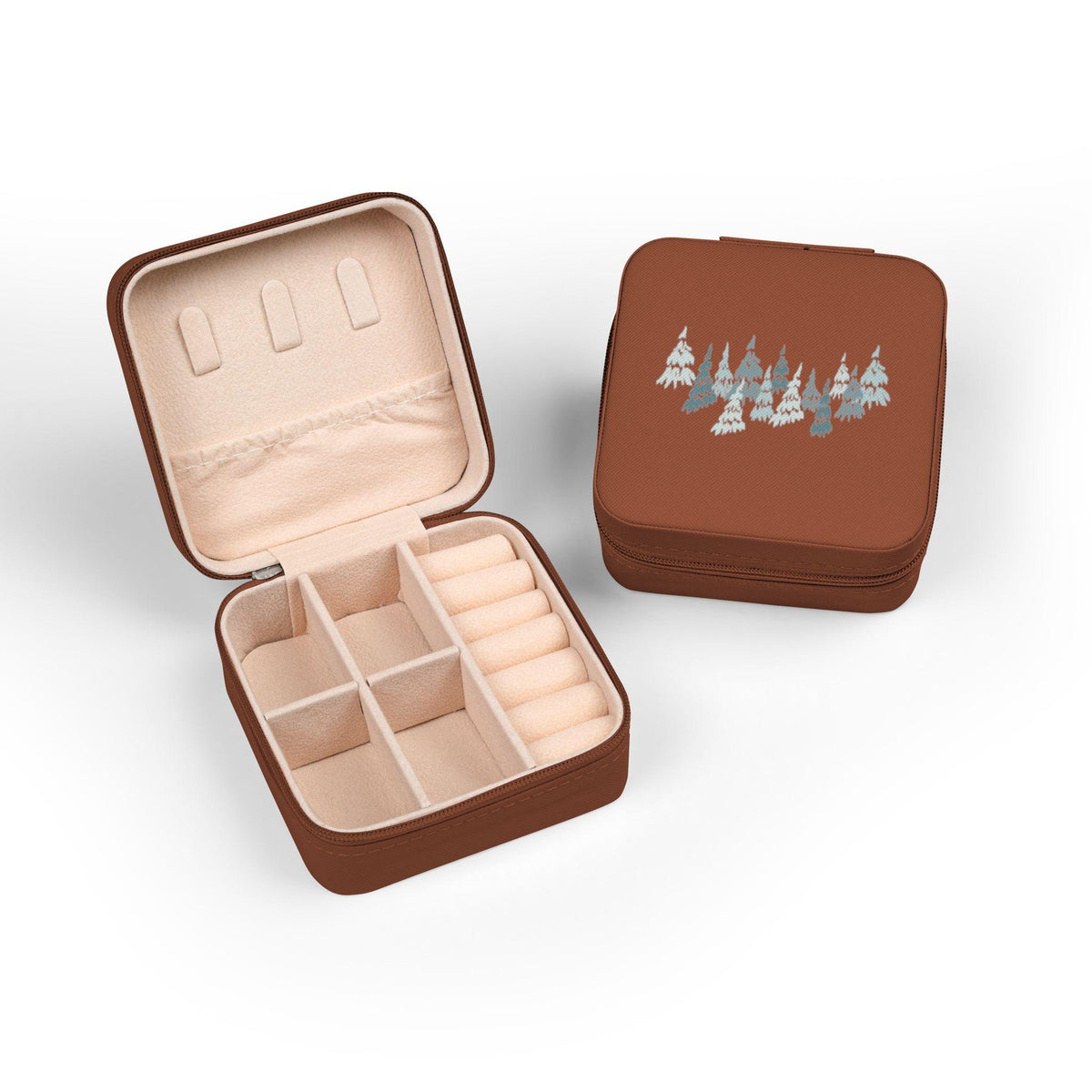 A brown, square jewelry box with a zipper closure, open to reveal compartments and ring holders. The closed box has a forest design on the lid. The interior is a light beige color.