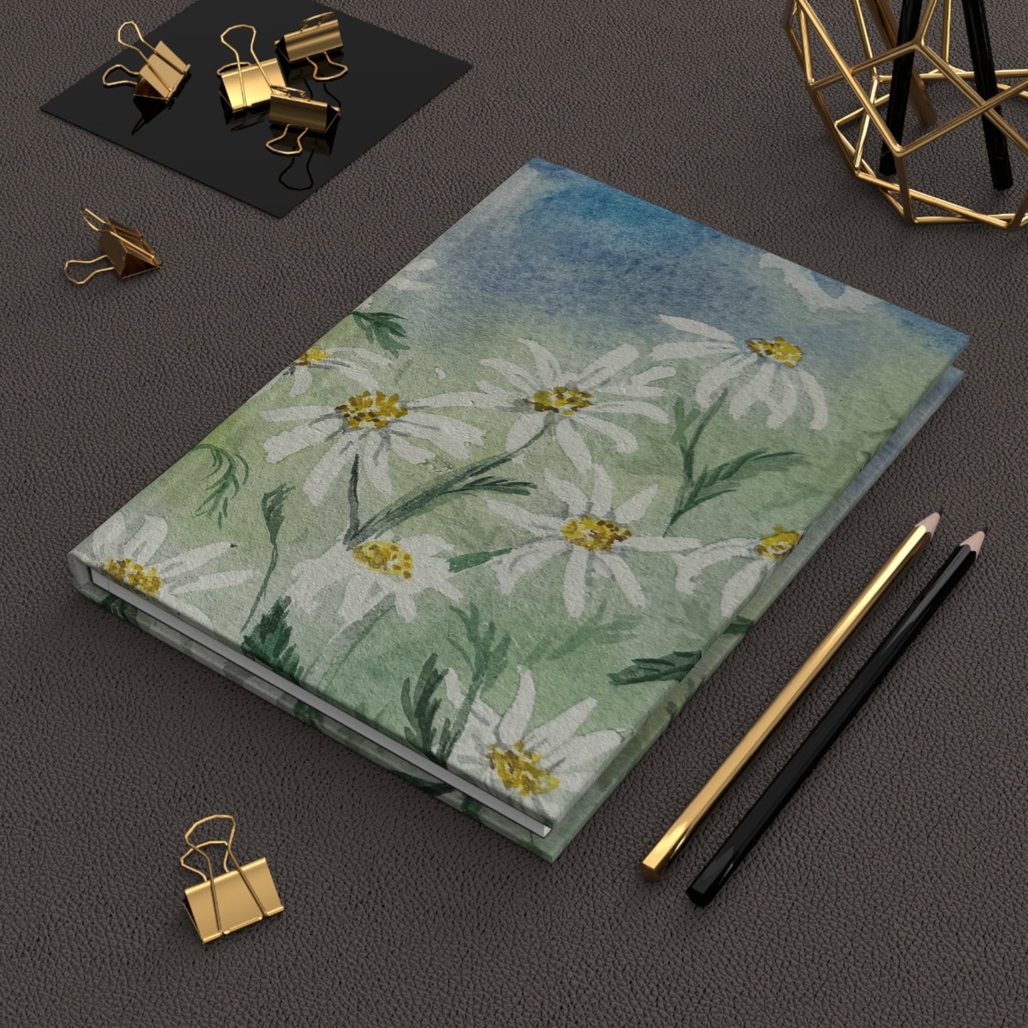cottage style floral journal with daisy field artwork Notebook with floral design on a dark surface with office supplies