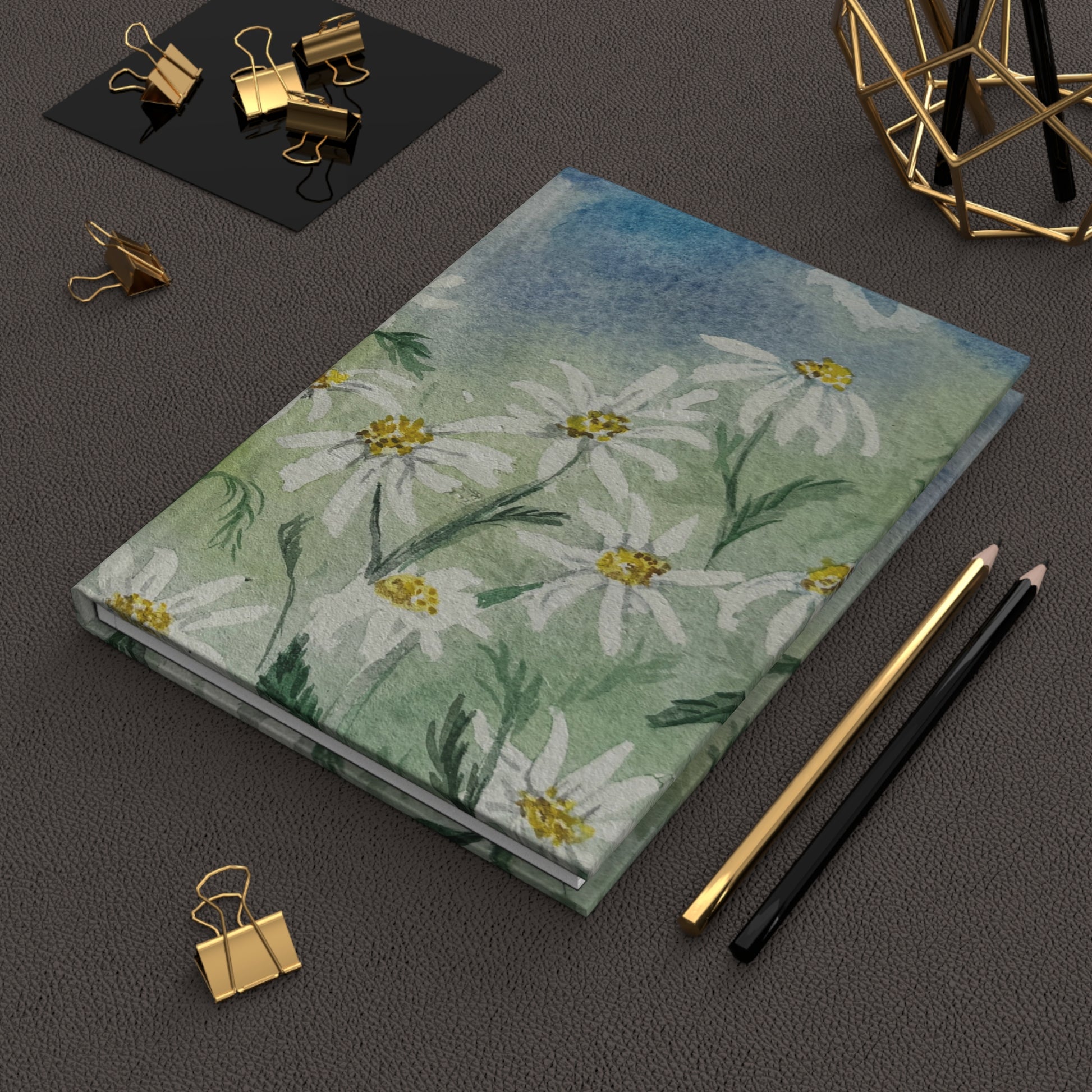 cottage style floral journal with daisy field artwork Notebook with floral design on a dark surface with office supplies