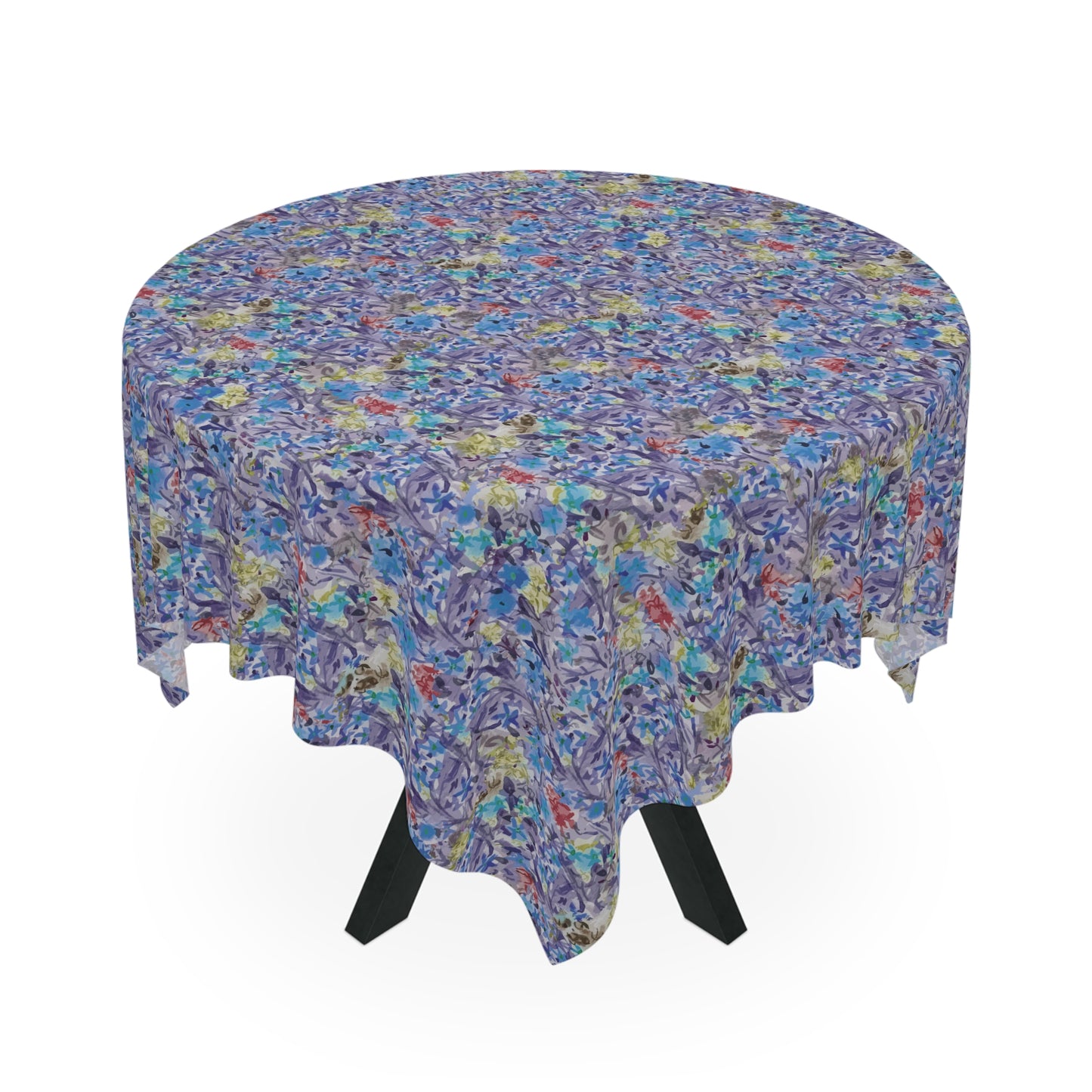 Round table covered with a blue watercolor floral tablecloth featuring botanical patterns in blue, lavender, and green tones.