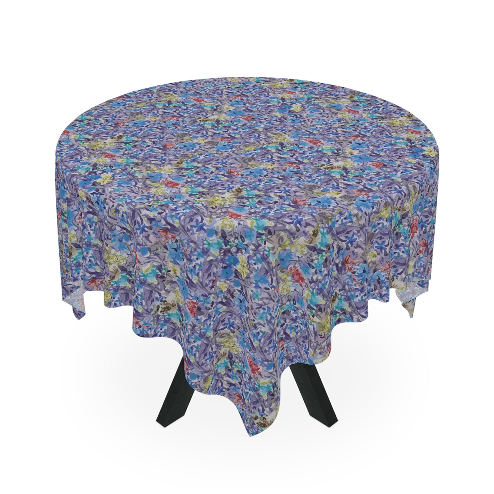 Round table covered with a blue watercolor floral tablecloth featuring botanical patterns in blue, lavender, and green tones.