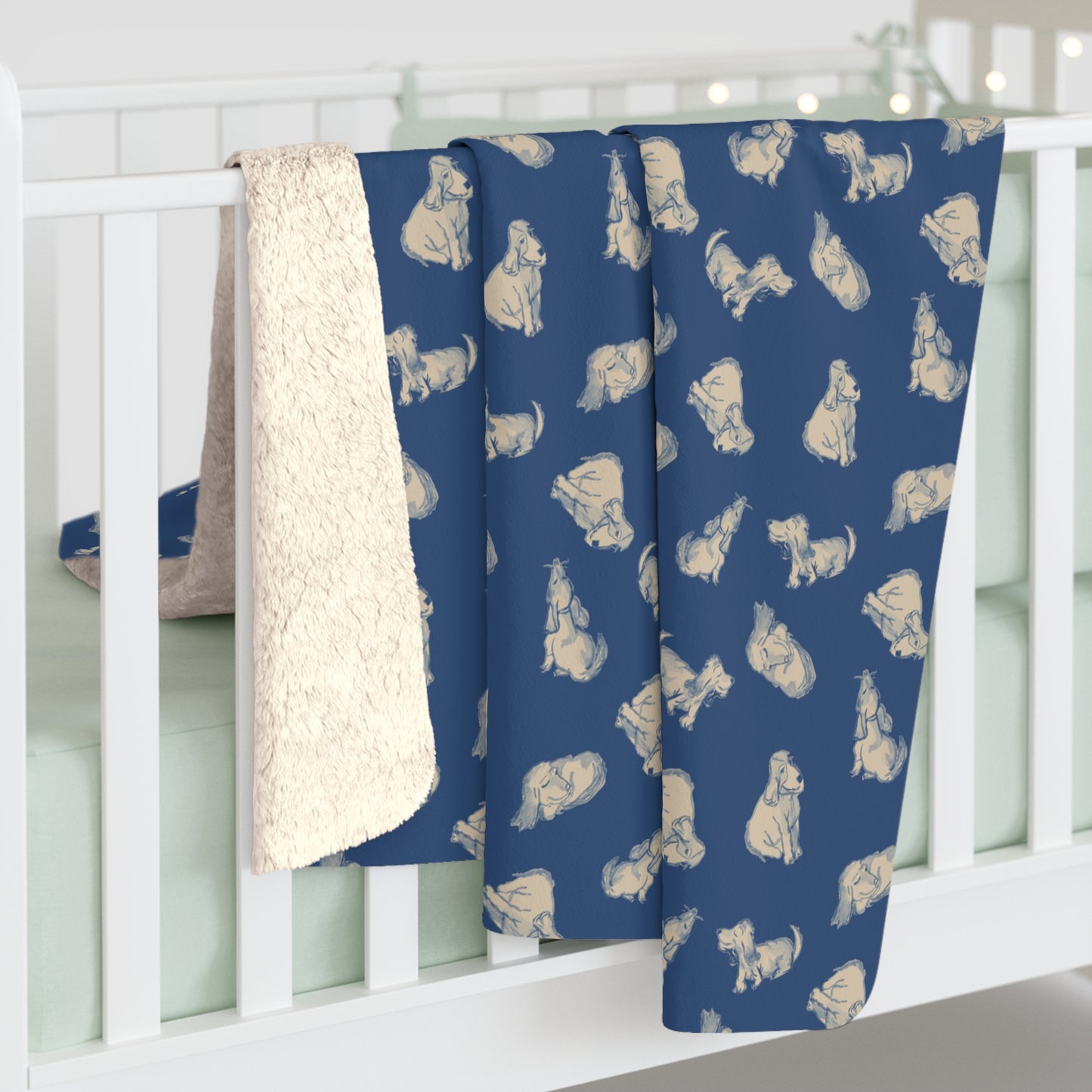 Blue baby blanket with white dog pattern draped over a crib