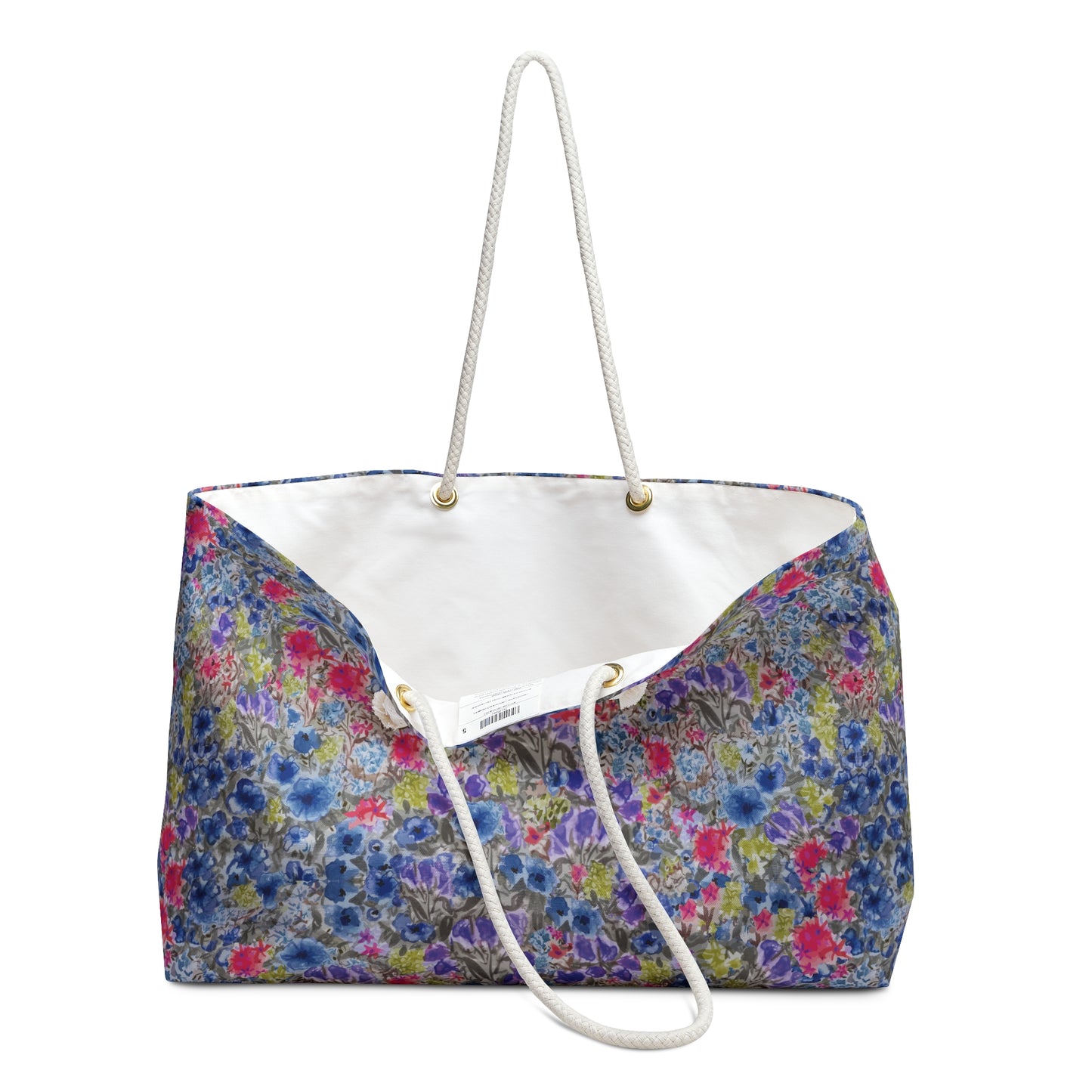 Blue and pink watercolor wildflower weekender bag with a vibrant meadow floral pattern and white rope handles, designed as a spacious travel tote for beach trips and weekend getaways.