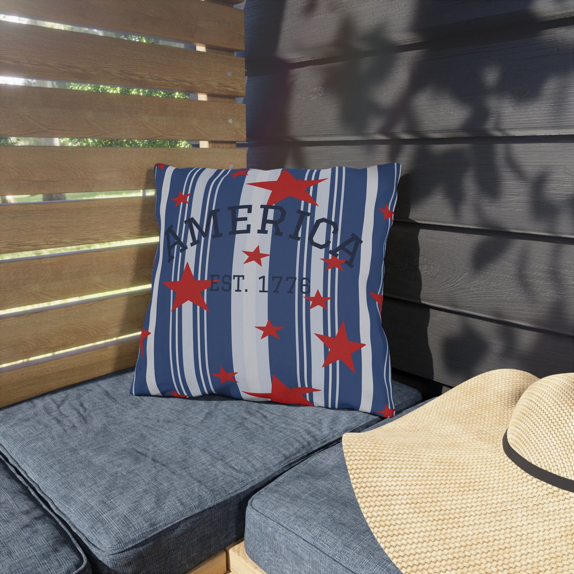 Decorative pillow with star pattern and 'America' text on a gray cushioned bench.