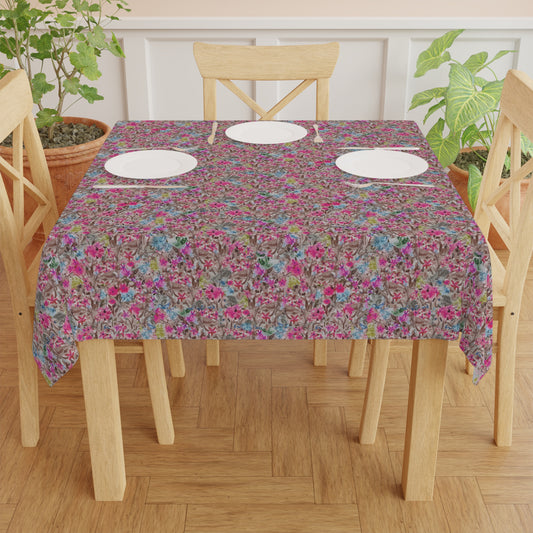 Table set with a floral tablecloth on a wooden table and chairs. Watercolor floral table cover with blooming branches in pink, blue, and neutral tones
