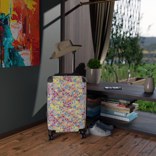 Floral-patterned suitcase with a hat on top in a room with books and a painting.
