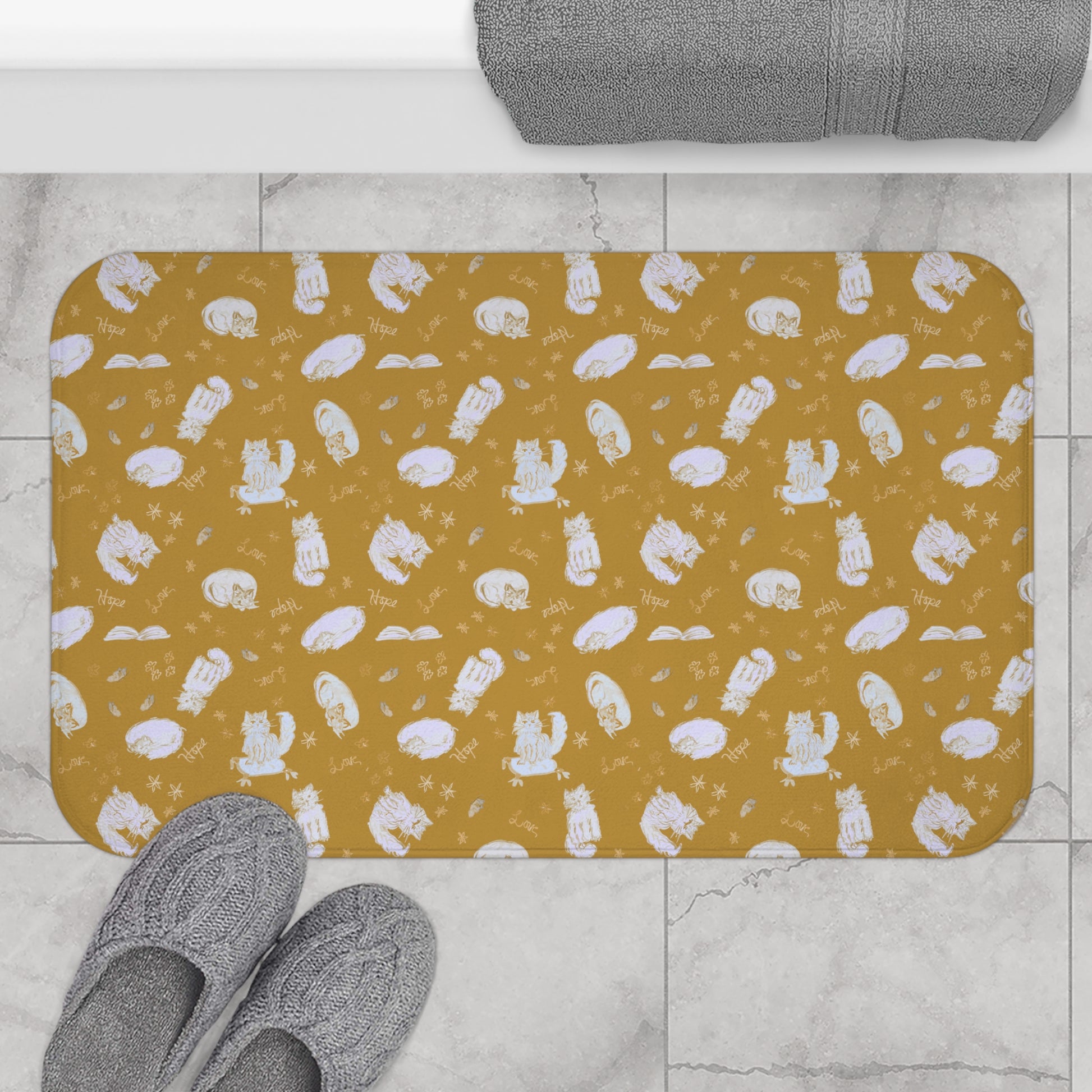Mustard yellow bath mat featuring a cozy repeating pattern of sleeping and fluffy cats, books, stars, leaves, and handwritten words on a warm golden background, perfect for cat lovers and cozy home décor.