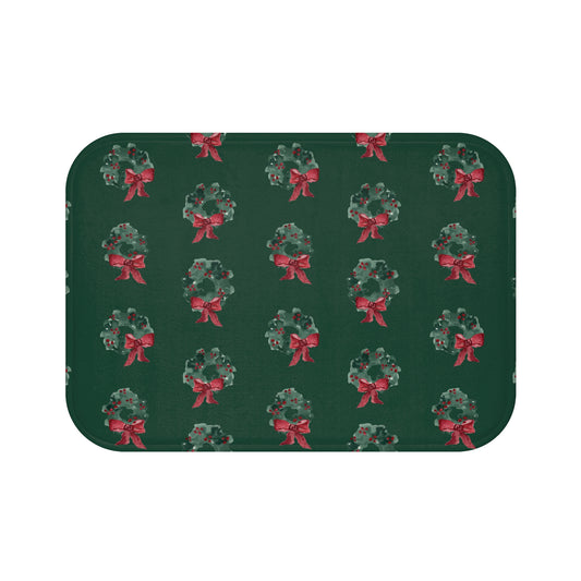 Bath mat with hand-painted evergreen wreaths and red bows on dark green