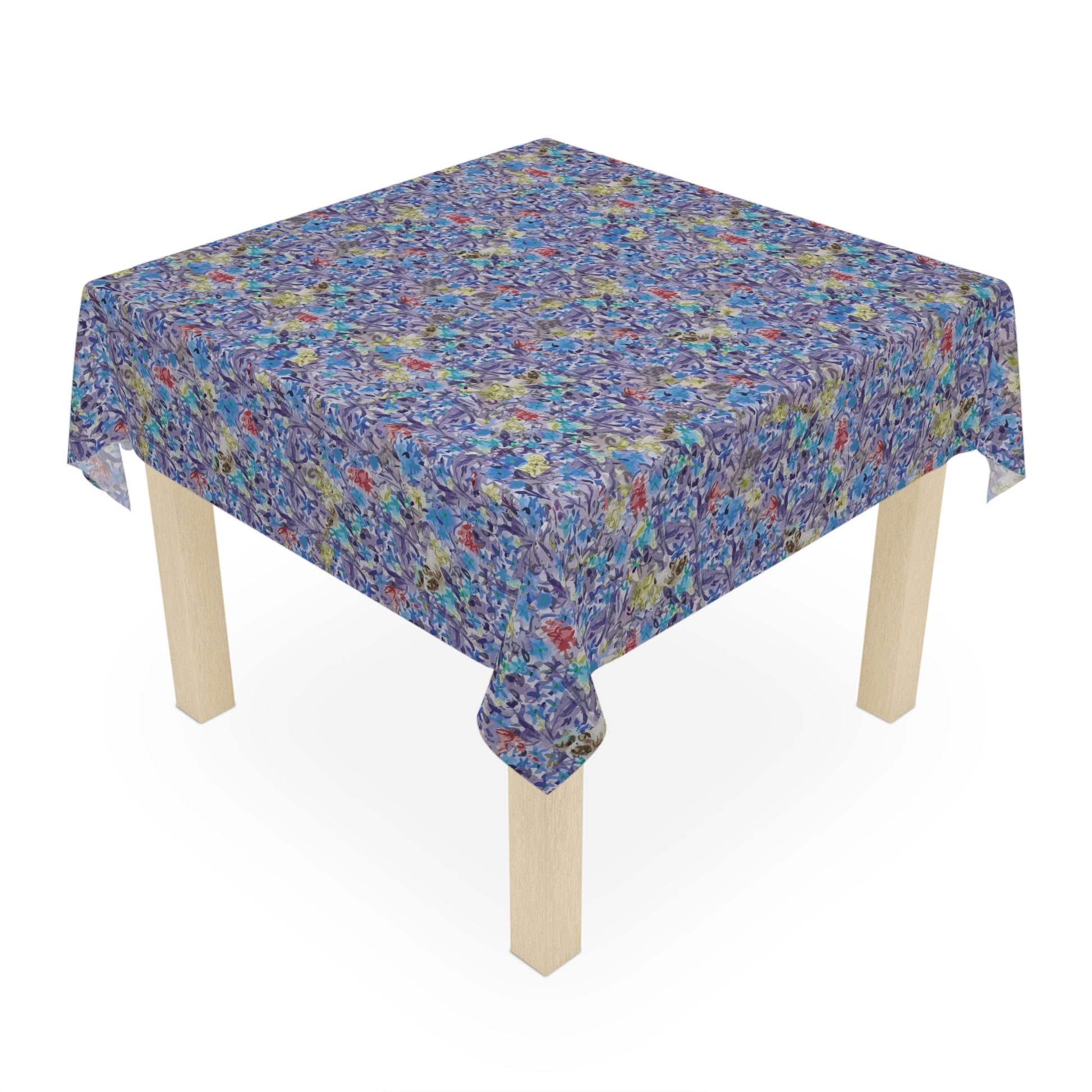 Round table covered with a blue watercolor floral tablecloth featuring botanical patterns in blue, lavender, and green tones.
