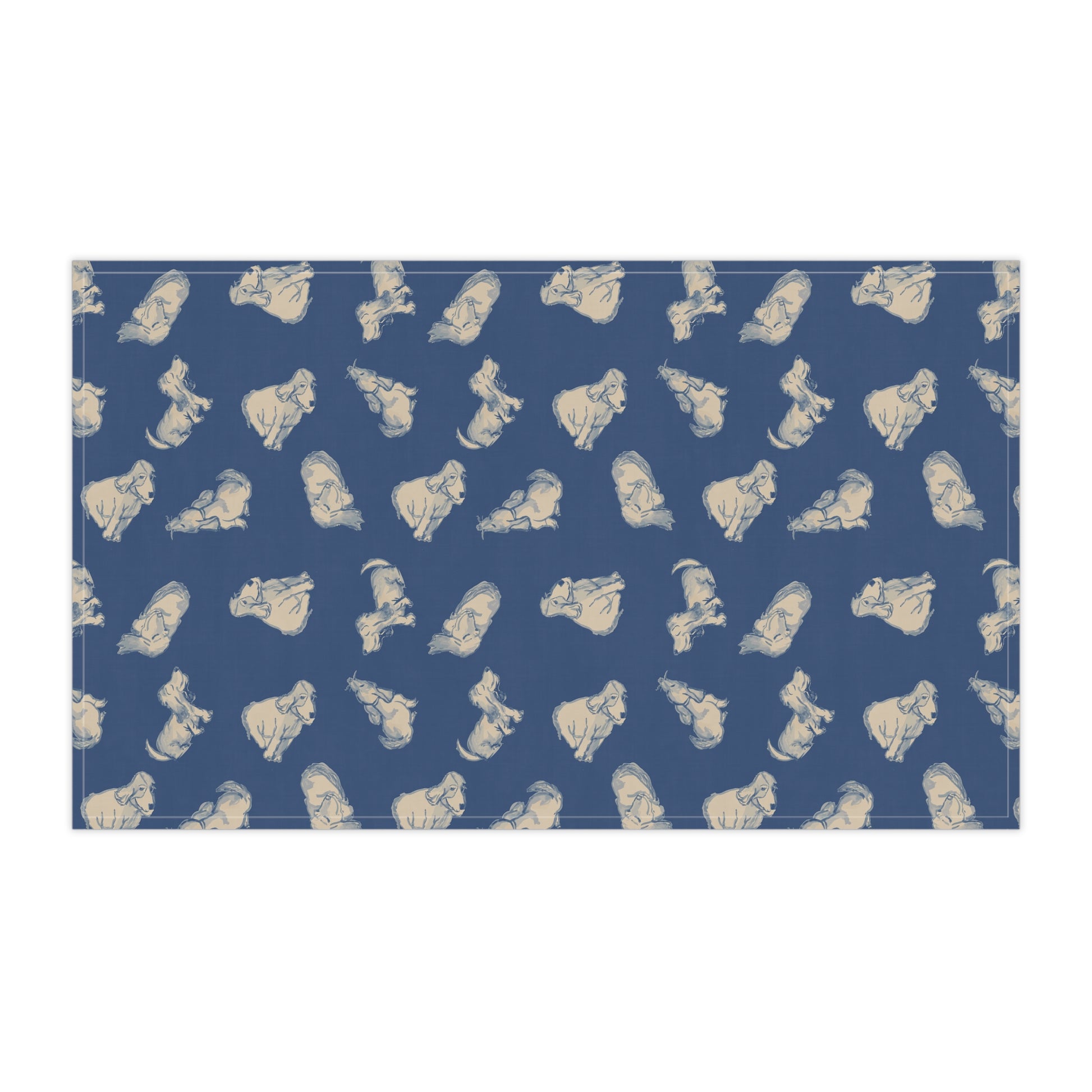 Navy blue kitchen tea towel featuring a repeating hand-drawn dog pattern in soft cream tones, displayed hanging in a bright kitchen with a wooden countertop, herbs, and fresh bread for cozy pet lover home décor.