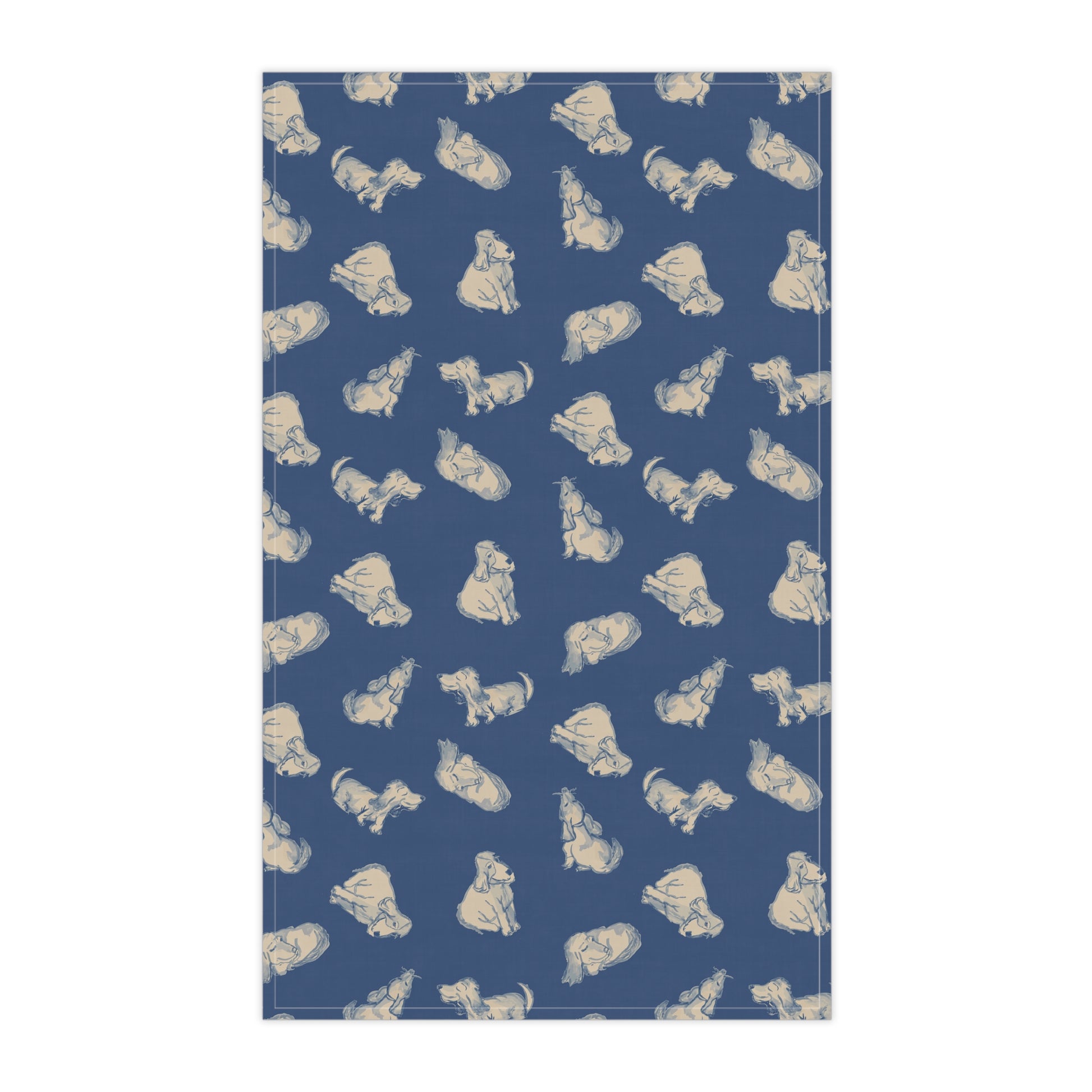 Navy blue kitchen tea towel featuring a repeating hand-drawn dog pattern in soft cream tones, displayed hanging in a bright kitchen with a wooden countertop, herbs, and fresh bread for cozy pet lover home décor.