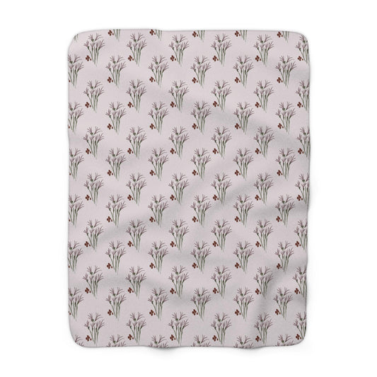 A rectangular blanket with a repeating pattern of stylized floral bouquets and small red berries on a light pink background. The blanket is made of a soft, plush material.