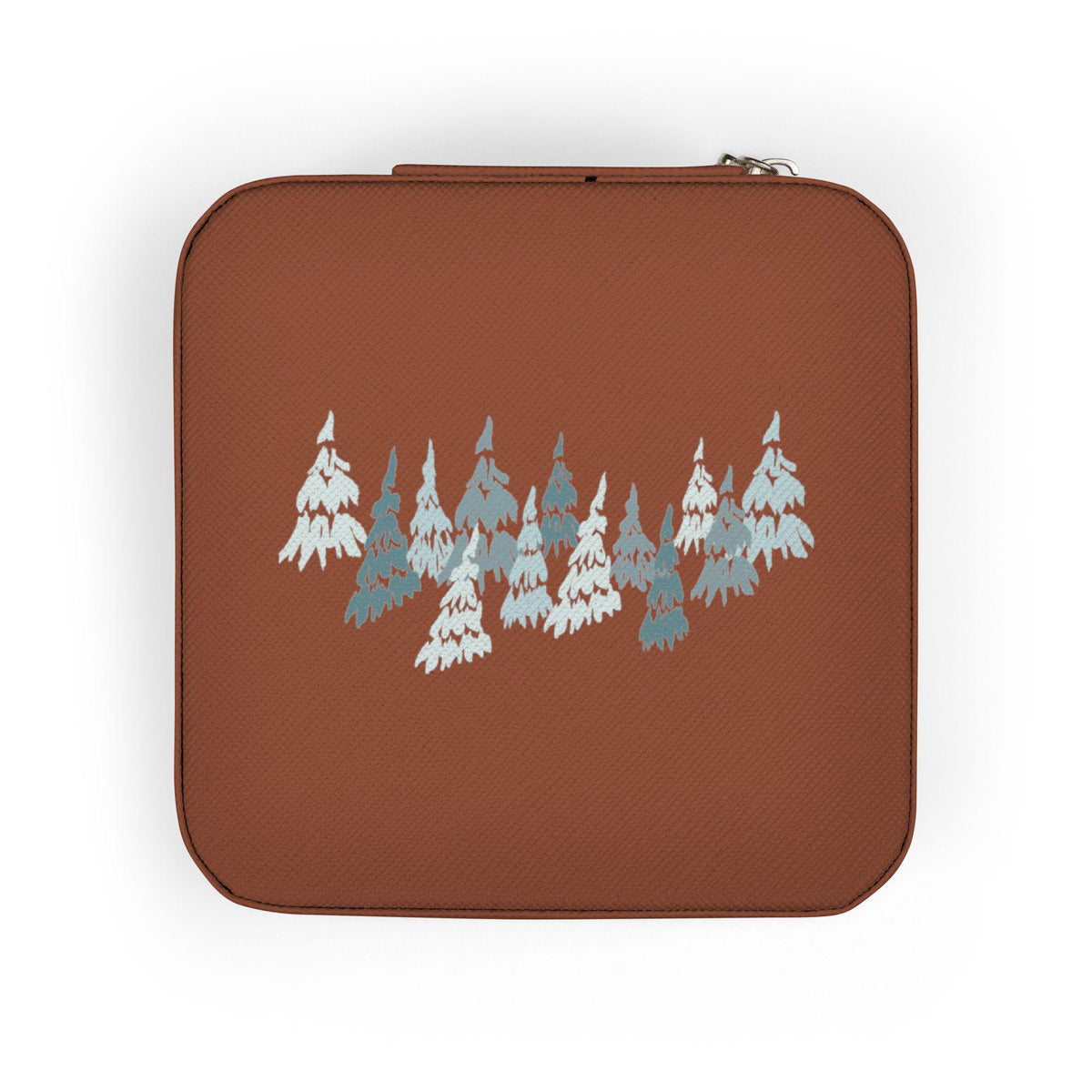 A square, rust-colored travel jewelry case with a zipper closure. The case features a repeating pattern of stylized, light blue and white evergreen trees across the front. The trees are arranged in a horizontal row.