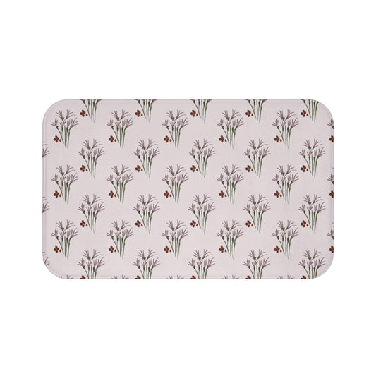 Rectangular bath mat with a repeating pattern of stylized purple floral sprigs and small red berry clusters on a light beige background. The mat has rounded corners and a soft, textured appearance.