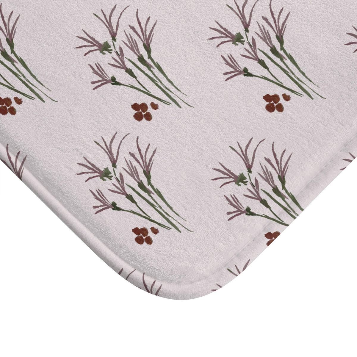 A light pink bath mat with a repeating pattern of watercolor-style floral elements. The design features clusters of purple and green stems with delicate purple leaves and small brown berry-like accents. The mat has a soft, plush texture.