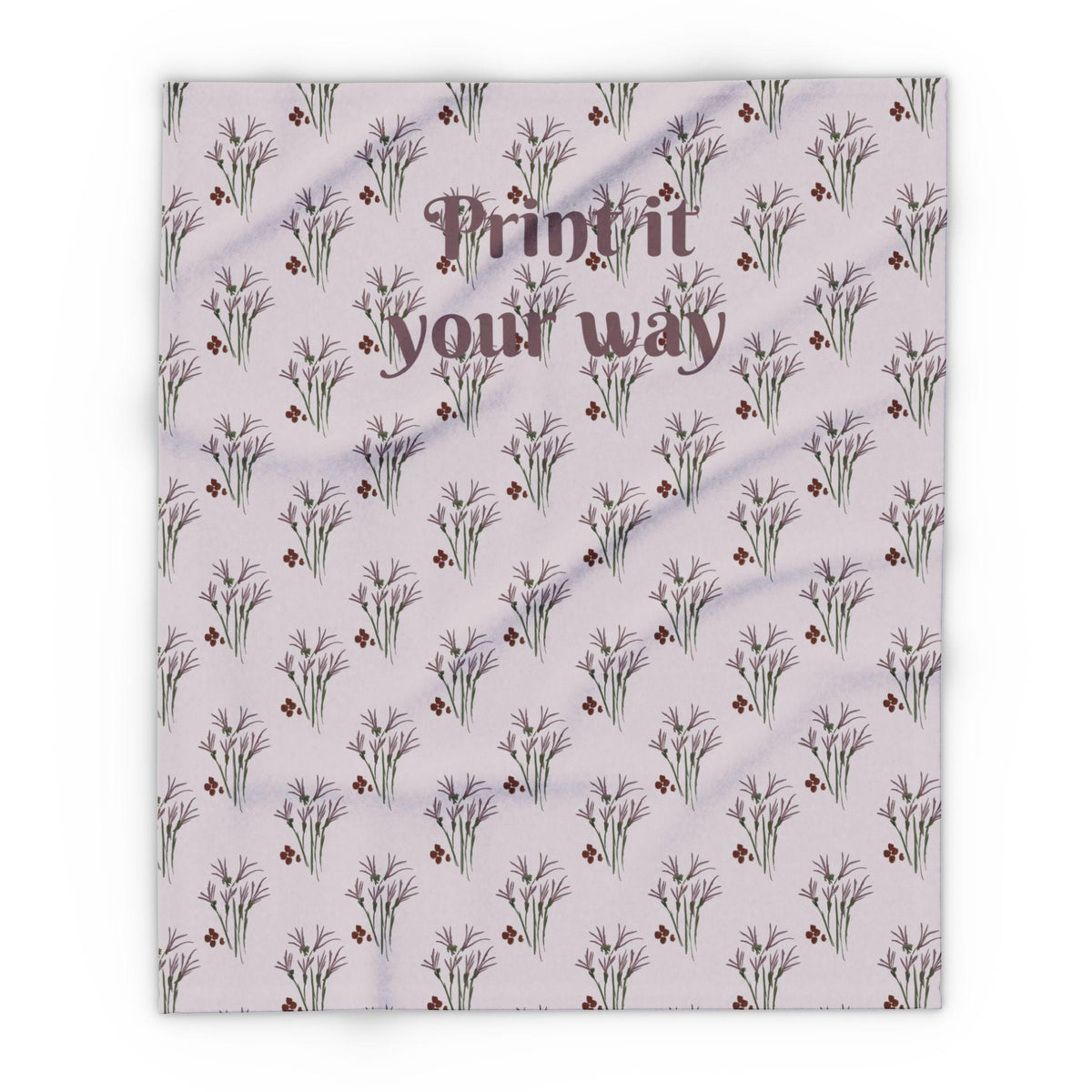 A light purple blanket with a repeating pattern of stylized floral sprigs in purple and brown. The blanket has the text "Print it your way" in a darker purple script across the center.