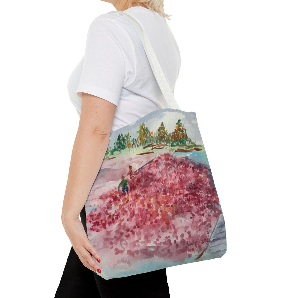 A white tote bag featuring a watercolor painting of a cranberry bog. The artwork depicts a field of red berries, a person in a green shirt, and trees. The bag has a white strap and is carried over the shoulder.