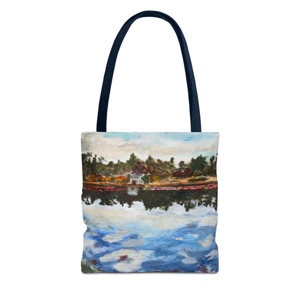 Tote bag featuring a landscape painting of a lake with trees and a small building on the shore. The painting has a watercolor style with blue, green, red, and white colors. The bag has a navy blue handle.