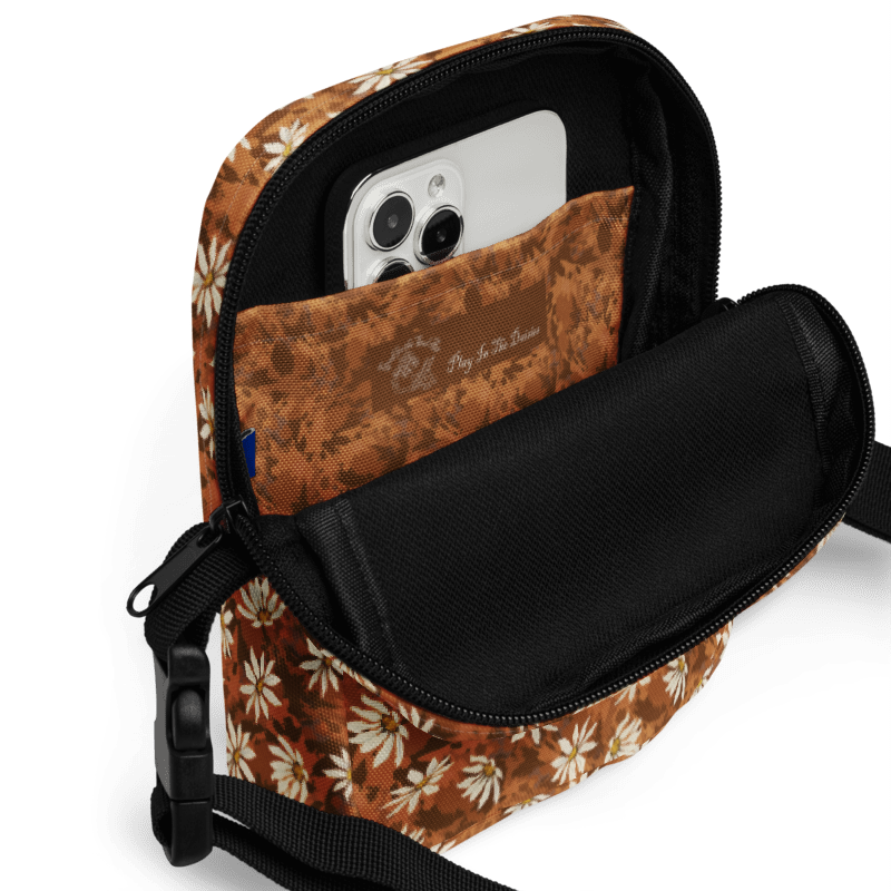 Daisy-scatter on textured warm browns bag with a black strap on a white background